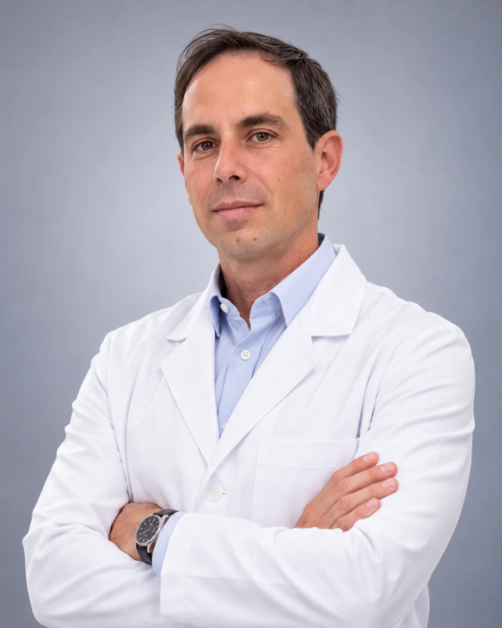 Dr. Gabriel Jarreta Lima, cirurgião-dentista em Orlândia, de jaleco branco e braços cruzados